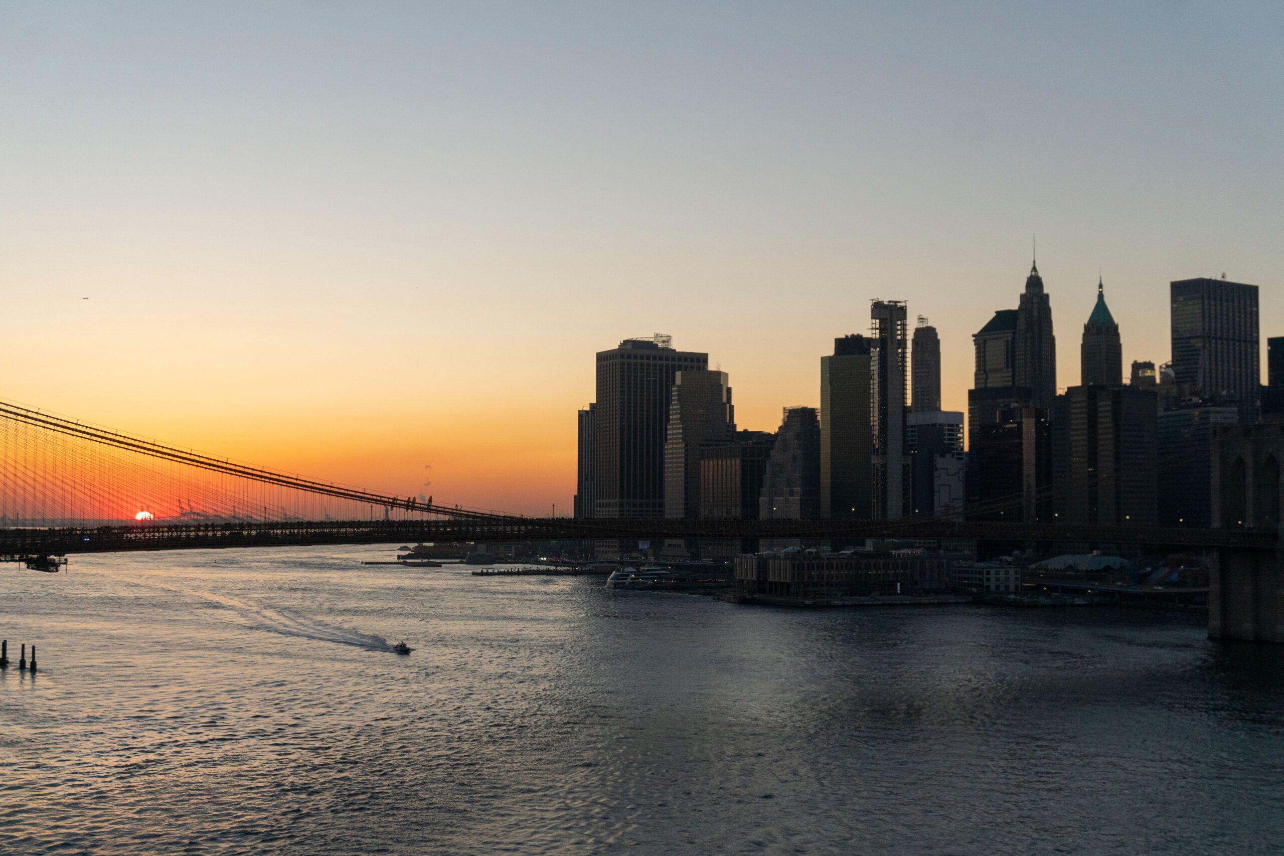 Stunning view of Brooklyn Bridge and Manhattan skyline captured during sunset over the New York City waterfront.