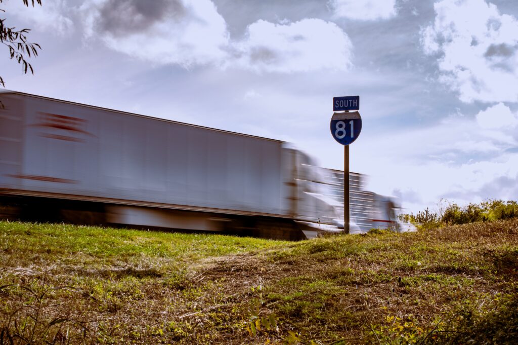 Blurred truck on Interstate 81 South with clear blue sky and grassy foreground.