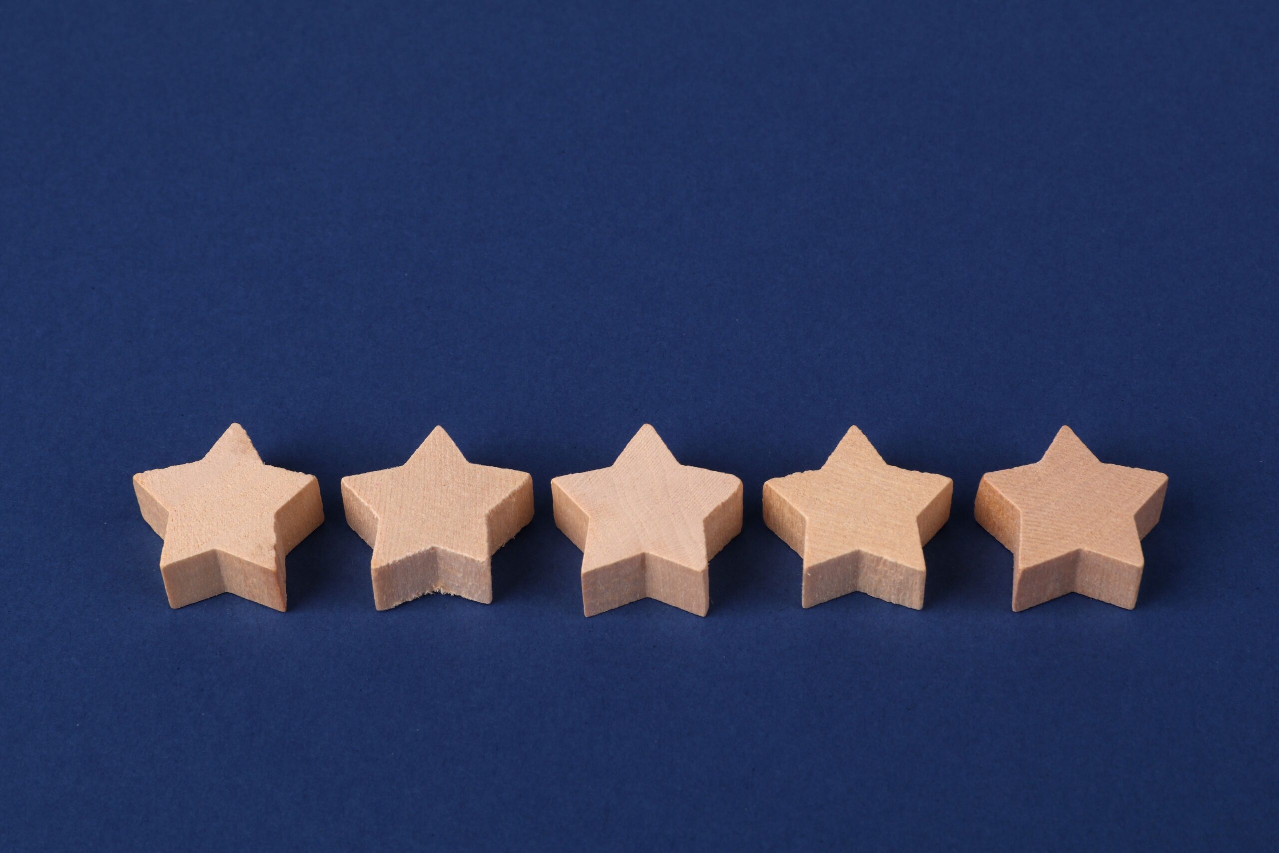 Five wooden stars on a blue background representing a rating system or evaluation concept.
